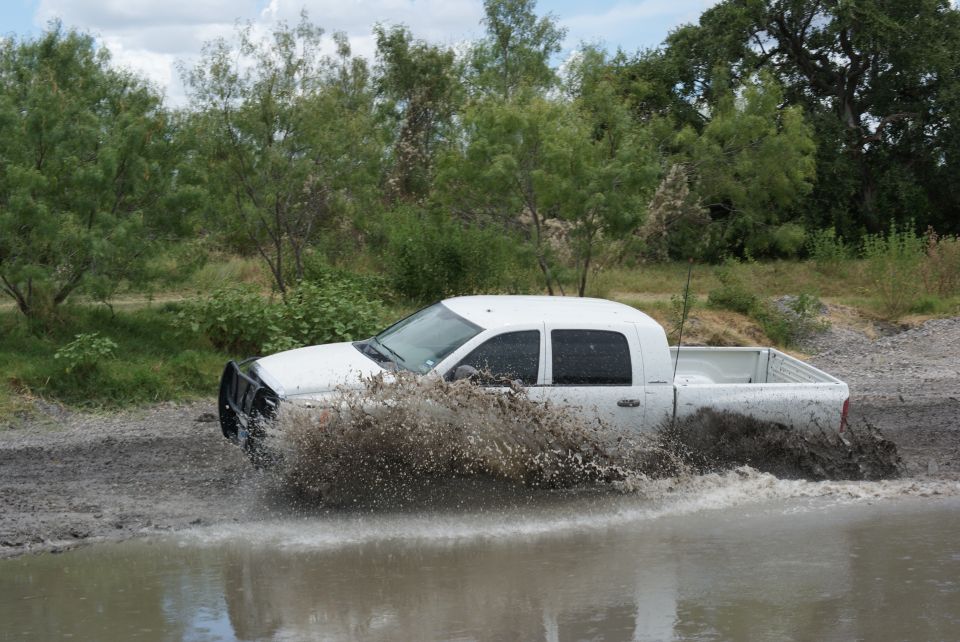 White pickup truck splashing through mud puddle