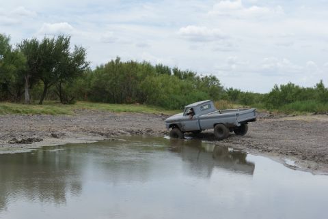 1989 Ford Bronco - Pickup truck attempts to drive through a muddy water obstacle.