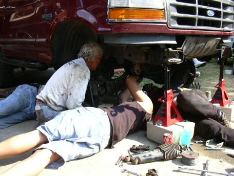 1991 Ford Bronco - Mechanics work on the suspension of a lifted 1991 Ford Bronco during a lift kit installation.