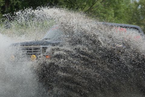 1989 Ford Bronco - A 1989 Ford Bronco navigates through a large splash of water, its off-road capabilities.