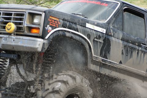 1989 Ford Bronco - Mud flies as a Ford Bronco navigates off-road terrain. The "BRONCO" badge is visible on the side.