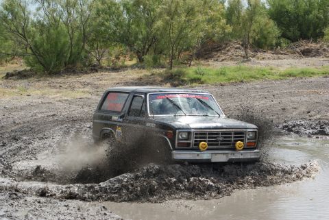 1989 Ford Bronco - This classic Ford Bronco navigates a challenging off-road mud course, kicking up a large spray.