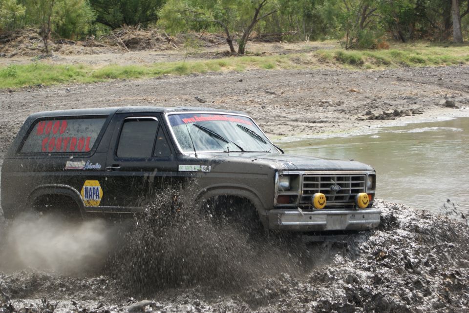 Black Ford Bronco driving through mud, with NAPA logo and red text on window