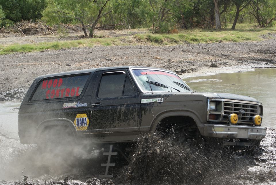 1989 Ford Bronco driving through mud, with "WOOD CONTROL" and NAPA logos on the side