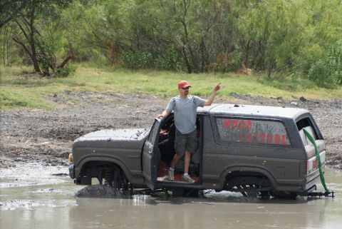 1989 Ford Bronco - This 1989 Ford Bronco is deep in the mud with a man standing in the open door.