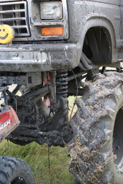 1989 Ford Bronco - This heavily modified truck, likely from the 1980s, is covered in mud, its lifted suspension and large off-road tires.