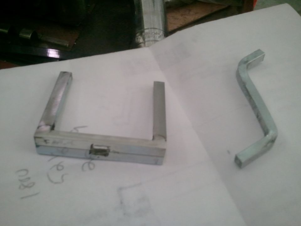 Metal bracket and bent metal tool on paper with handwritten numbers