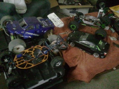 1985 Ford Bronco - A collection of RC vehicles, including a purple Pro-Line truck and a black touring car, are arranged on a surface.