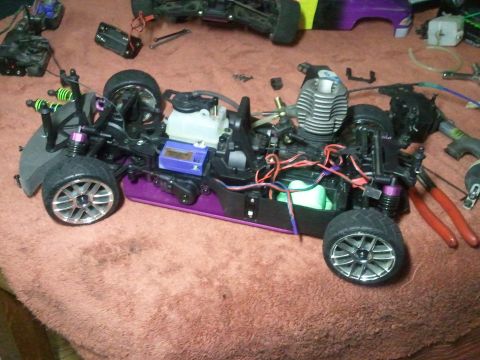 1985 Ford Bronco - RC car chassis with engine and suspension components disassembled on a red towel.