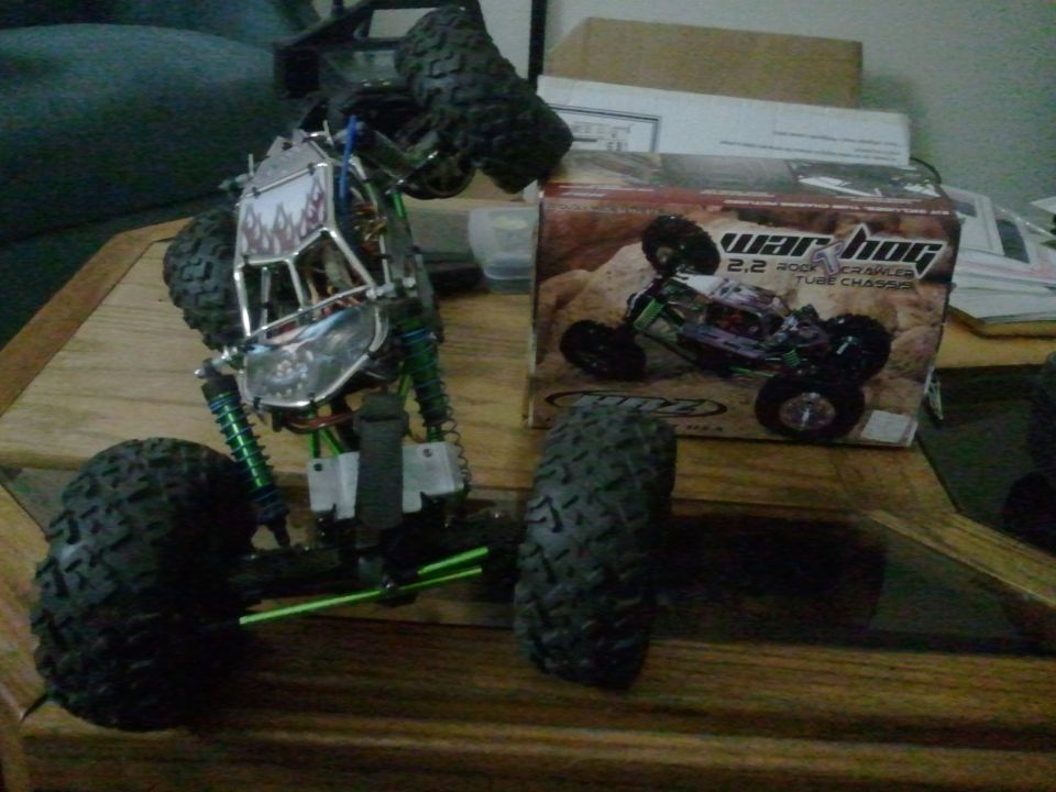 Remote control rock crawler toy with green shocks and a box labeled 'war hog 2.2 rock crawler tube chassis'