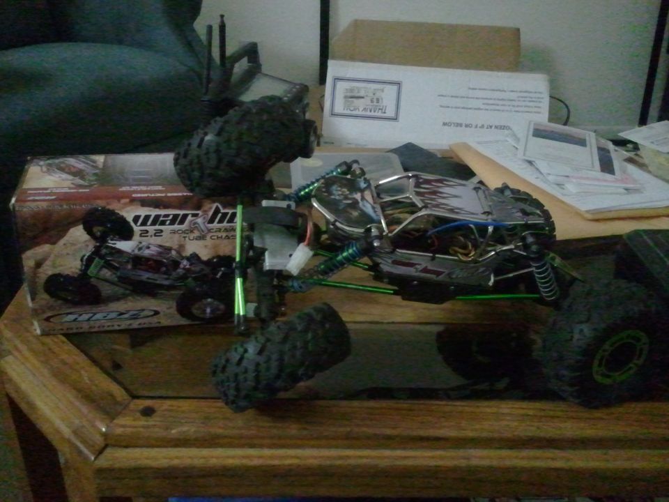 RC rock crawler toy car with large tires and exposed chassis, next to its box