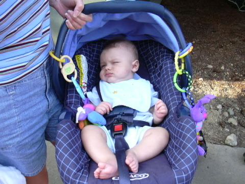 1991 Ford Bronco - A baby sits in a car seat, looking sleepy, with toys attached to the side.