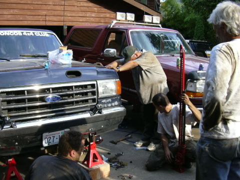 1991 Ford Bronco - Two men work on a 1991 Ford Bronco, with another Bronco visible behind it.