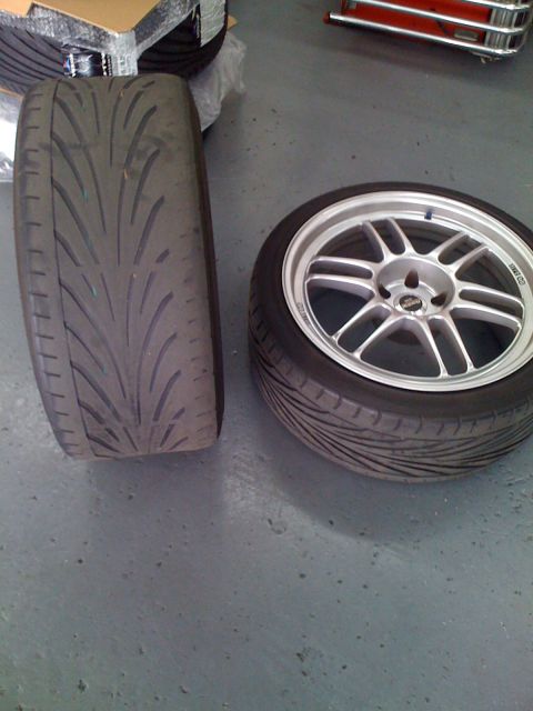 1990 Ford Probe - Two tires are shown, one is mounted on a silver Enkei wheel. The other tire is lying on its side.