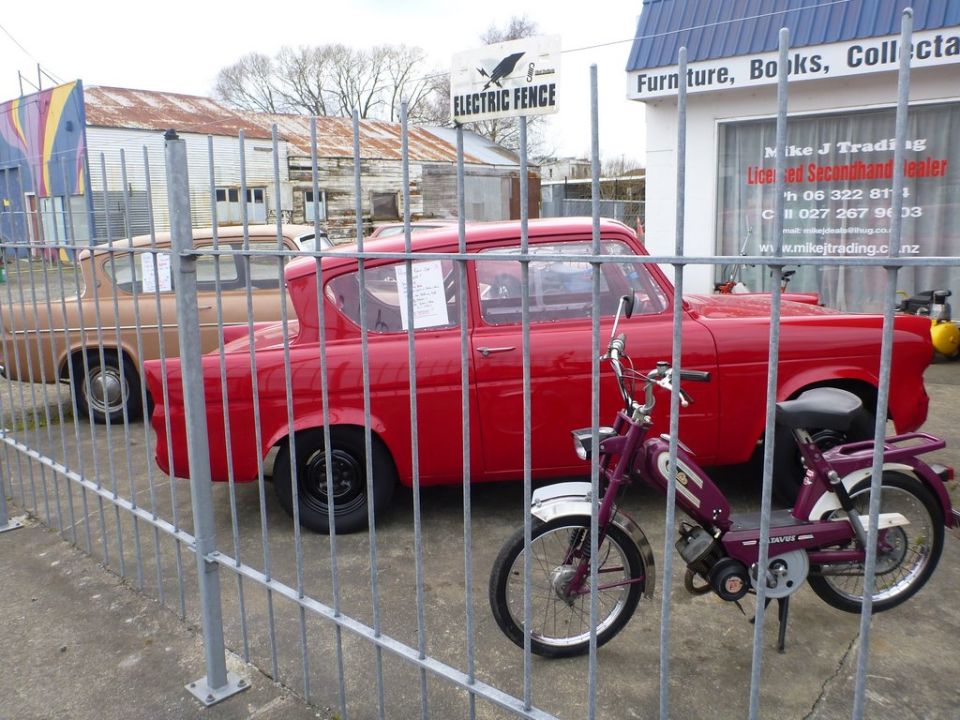 red sedan and tan sedan parked behind metal fence, purple moped in foreground
