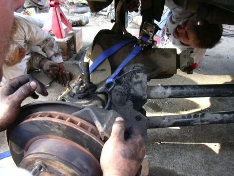 1991 Ford Bronco - Mechanics are working on the suspension of a vehicle, possibly a Ford Bronco.