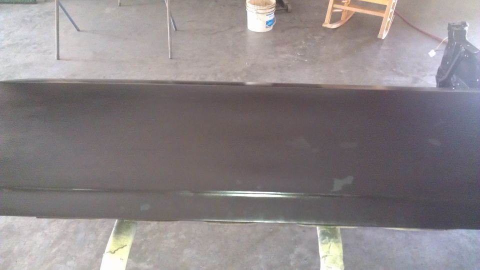 Dark car door on a stand, showing primer and some scuffs
