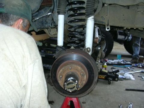 1991 Ford Bronco - Close-up view of a vehicle's front wheel hub and suspension system being worked on.