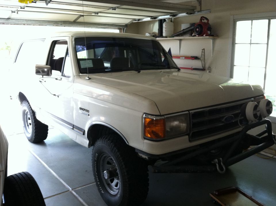 White Ford Bronco SUV parked in garage, 3/4 front view with brush guard