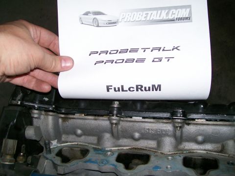 1995 Ford Probe - A document with "PROBETALK PROBE GT" is held over a car engine part.