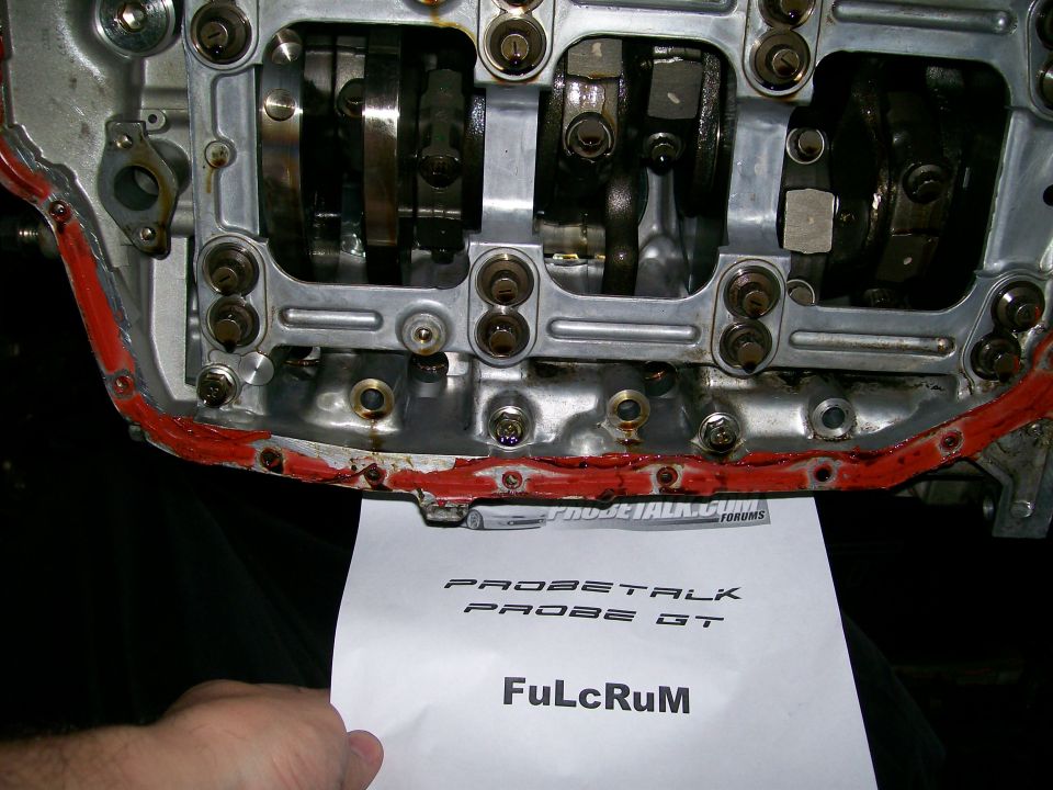 Aluminum cylinder head with camshafts exposed and red RTV on the flange, ProbeTalk sale sheet held below