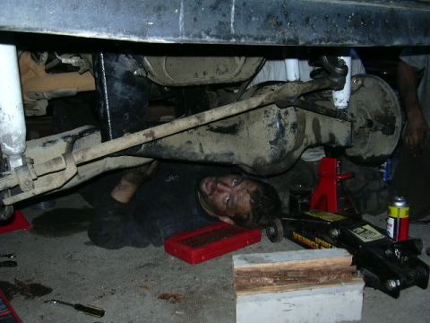 1991 Ford Bronco - A person is working underneath a vehicle that is supported by jacks and blocks.