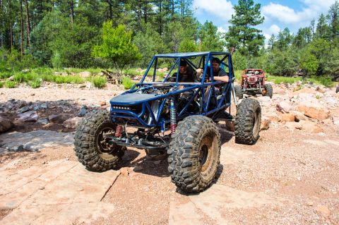 1966 Ford Bronco - Two off-road buggies navigate a rocky trail through a wooded area.