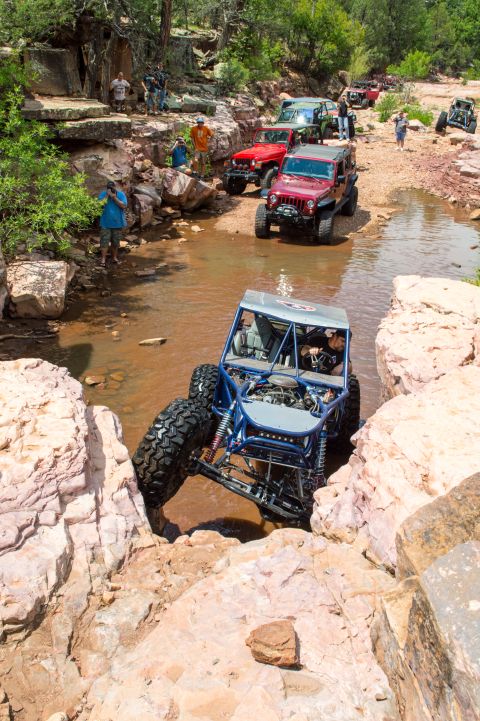 1966 Ford Bronco - Multiple off-road vehicles navigate a rocky stream bed during an excursion.