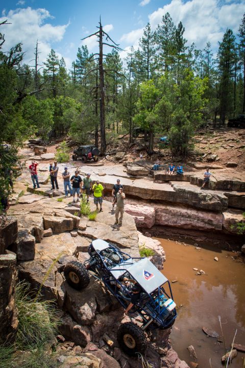 1966 Ford Bronco - A group of people watch an off-road buggy navigate a challenging rocky course near a stream.