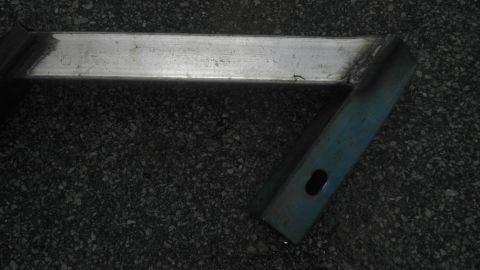 1989 Ford Bronco - A metal bracket is visible on a dark, pebbly surface.