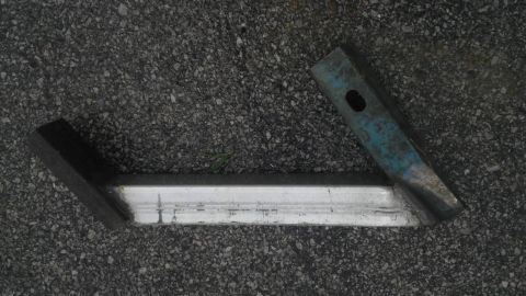 1989 Ford Bronco - Two jack stands are resting on a dark, pebbly surface, likely asphalt.