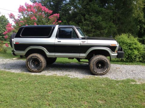 1979 Ford Bronco - This lifted Ford Bronco is parked on a gravel driveway with grass and trees in the background.