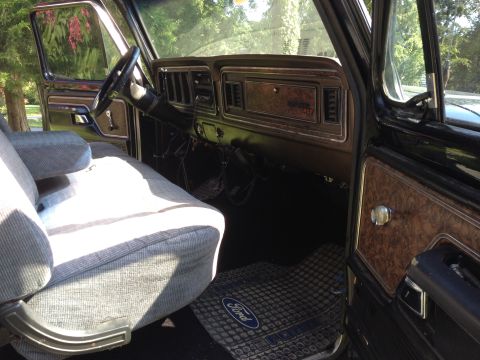 1979 Ford Bronco - The interior of a 1979 Ford Bronco shows its grey striped seats and wood grain dashboard accents.