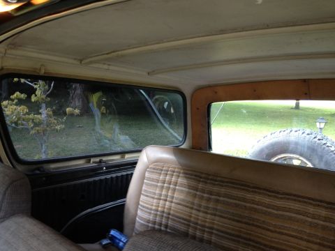1979 Ford Bronco - Interior view of a vehicle, showing plaid seats and a spare tire visible through the rear window.