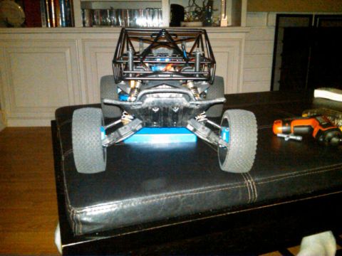 1986 Ford Bronco - This remote control buggy is sitting on a dark leather surface with a drill to the right.