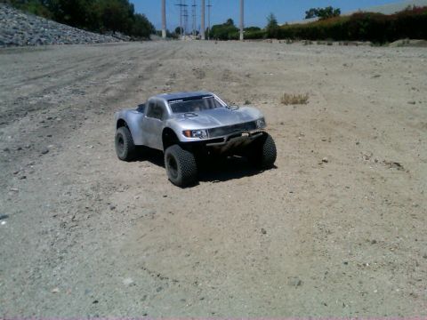 1986 Ford Bronco - A remote control truck sits on a dusty, unpaved surface under a bright sky.