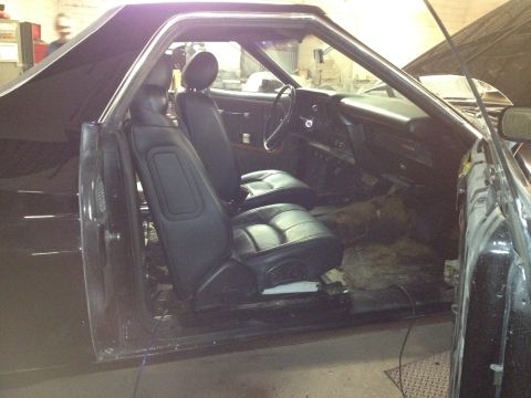 1975 Ford Ranchero - The interior of a vehicle is shown with the driver's side door open, revealing the seats and dashboard.