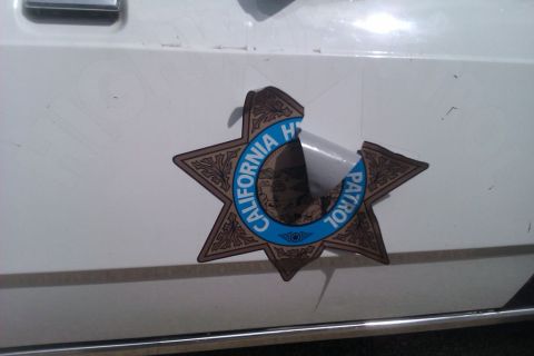 1991 Ford LTD Crown Victoria - Close-up of a California Highway Patrol badge on a white vehicle, showing wear and tear.