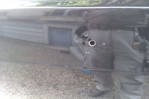 1991 Ford LTD Crown Victoria - A close-up of a car door shows multiple drilled holes, with a reflection of a garage in the background.