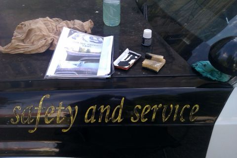 1991 Ford LTD Crown Victoria - Supplies are laid out on the hood of a police car, which has "safety and service" written on its side.