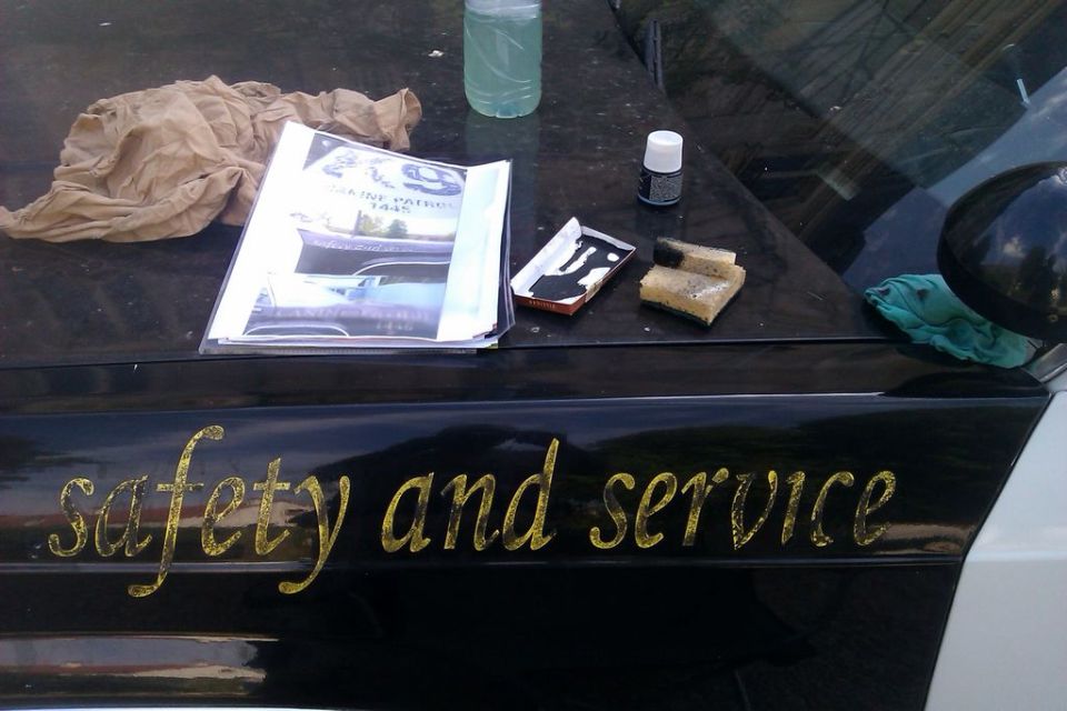 police car hood with a bottle of cleaner, ink pad, sponges, and a booklet