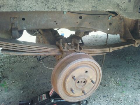 1979 Ford Bronco - Close-up of a heavily rusted vehicle's rear axle and suspension components.