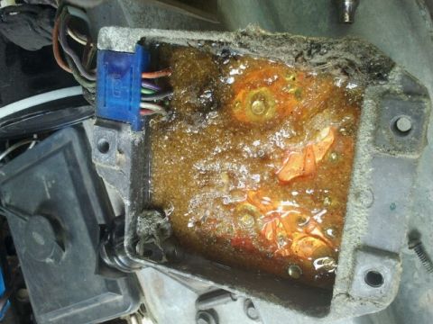 1979 Ford Bronco - This electronic control unit shows significant corrosion and damage, with melted orange material obscuring internal components.
