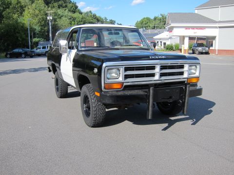 1987 Dodge 1500 - A two-tone black and white Dodge Ramcharger is parked in a lot with a pharmacy in the background.