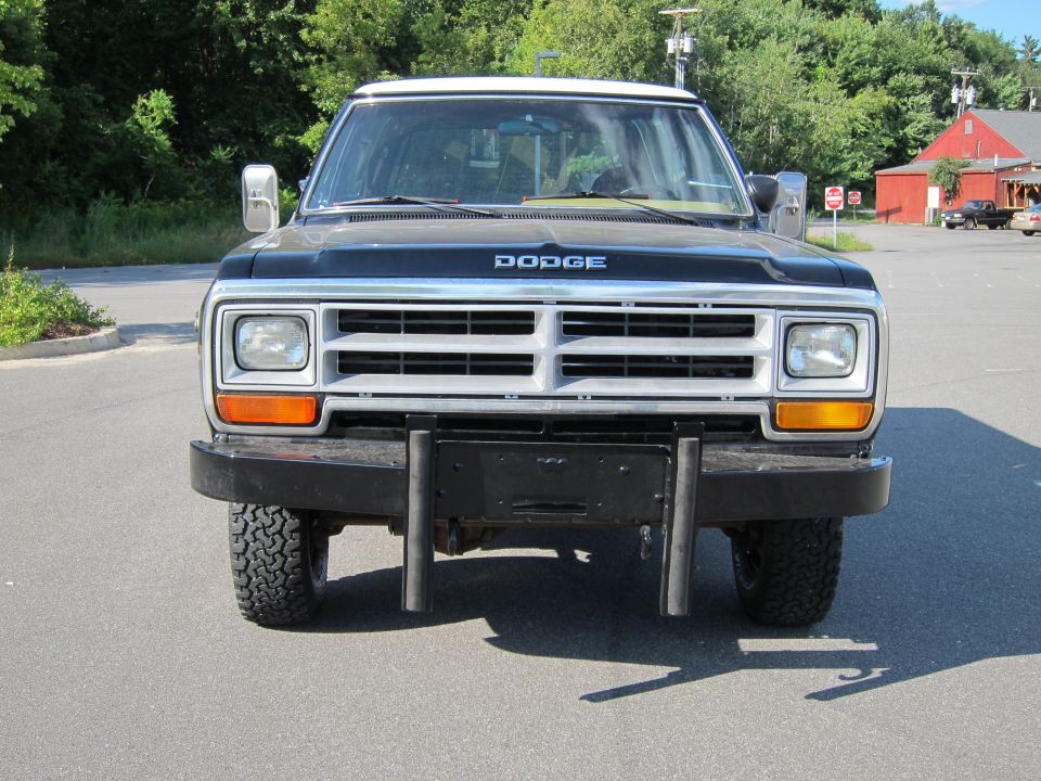 Black Dodge pickup truck front view, silver grille, aftermarket bumper, visible tires