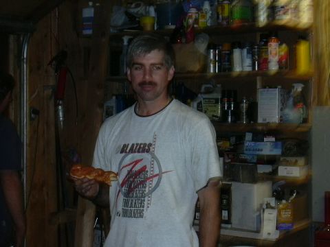 1991 Ford Bronco - A man stands in a garage, holding a pastry and wearing a t-shirt with 'Blazers' printed on it.