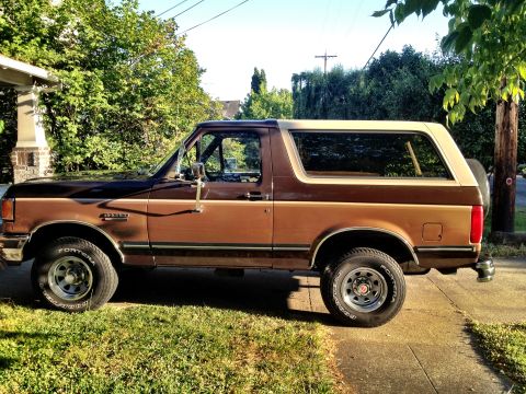 1991 Ford Bronco - Side view of a two-tone brown and tan 1991 Ford Bronco parked outdoors.