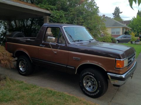 1991 Ford Bronco - A 1991 Ford Bronco with a two-tone brown and tan paint scheme is shown from a three-quarter front angle.
