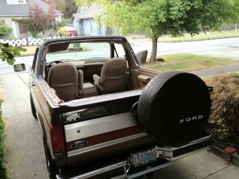 1991 Ford Bronco - Rear view of a 1991 Ford Bronco with its top removed and a spare tire mounted on the tailgate.
