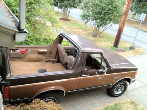 1991 Ford Bronco - The interior of this Ford Bronco is visible with the top removed, showing the front seats and cargo area.
